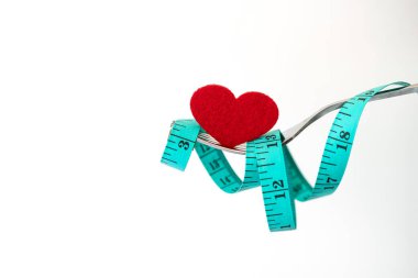 Kilo vermek için diyet, çatalla ölçüm bandı, kırmızı kalp şeklinde sağlıklı beslenme konsepti.
