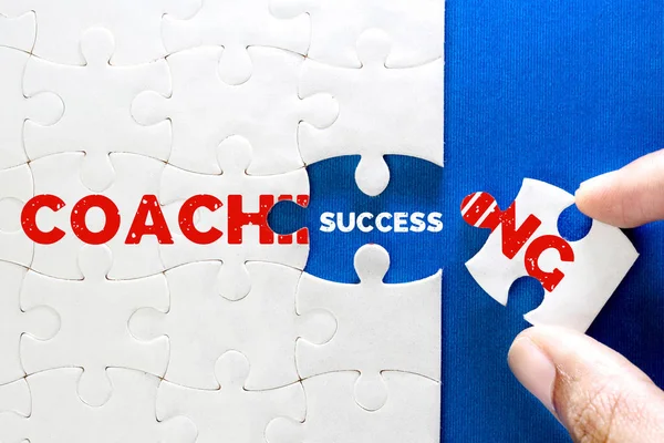Close up piece of white jigsaw puzzle with COACHING and SUCCESS text , concept of business coaching bring to  success completion , human resource training for personal development