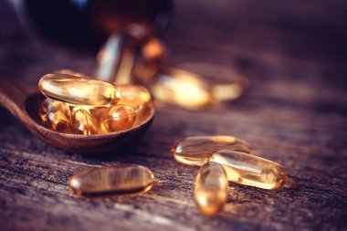 D vitamini ve Omega 3 balık yağı kapsüllerini iyi bir beyin, kalp ve sağlık için ahşap tabağa koyun.