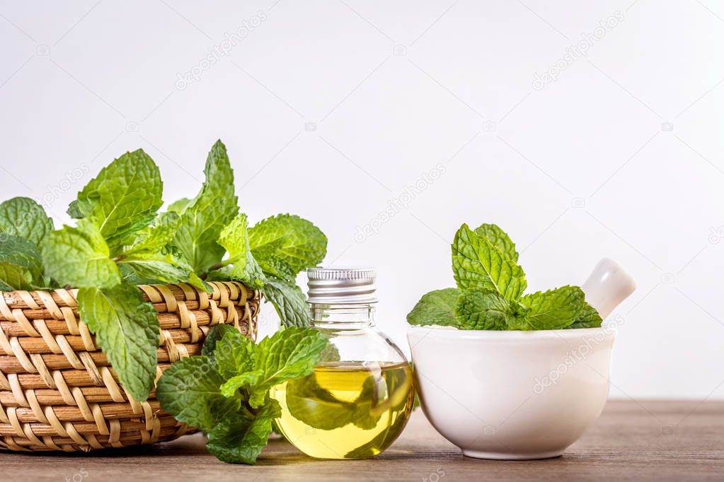 Aroma essential oil from peppermint in the bottle on the table with fresh green mint leaf