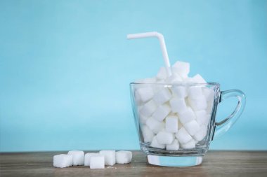 Cam açık mavi renkli ile ahşap masa, sağlıksız yiyecek konsepti 14 Kasım Dünya Diyabet günü kampanyası için küp beyaz şeker