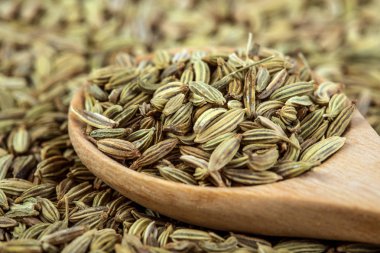 Kahverengi ahşap masadaki rezene tohumunu kaşıkla kapat.