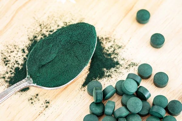 Spiulina tozu ve spirulina haplarını kaşığa doldur. Sağlıklı beslenme ve detoks konsepti.