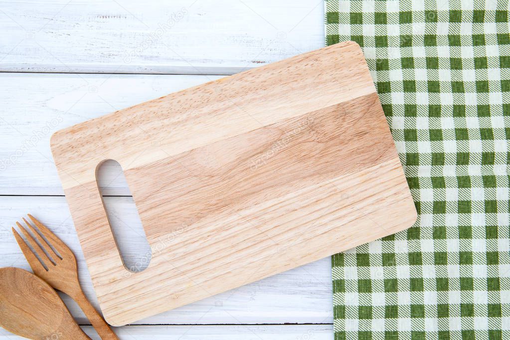 chopping board and tablecloth with wooden fork and spoon on white table , recipes food  for healthy habits shot note background concept