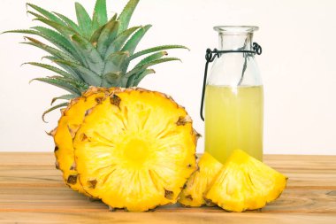 Bir ahşap üzerinde dilimlenmiş ananas meyve ile ananas suyu Şişeleri