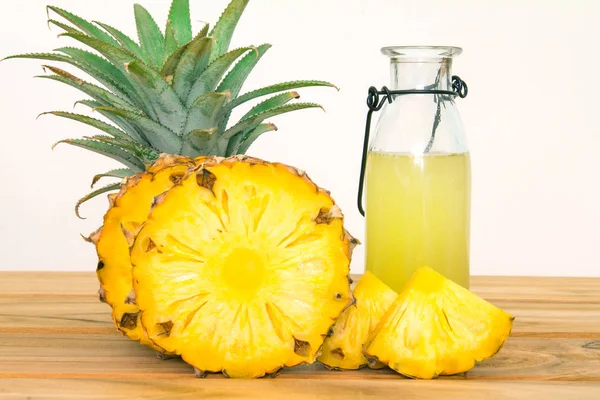 Бутылки ананасового сока с нарезанным ананасовым фруктом на дереве — стоковое фото