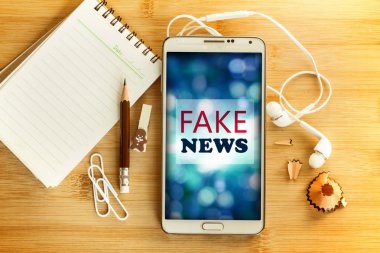 Boş not defteri ve kalem ile Akıllı telefonda Fake News Metin