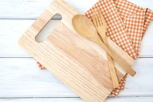 chopping board and tablecloth with wooden fork and spoon on whi