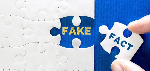 Close up a piece of white jigsaw puzzle with FACT FAKE text, co — стоковое фото