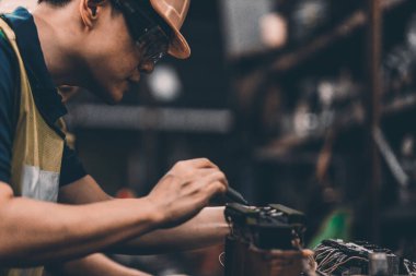 40 'lı yaşların başlarında fabrika fabrikasında çalışan bir erkek üretim bandı makinesini çalıştırıyor ve çalışmaya ayarlıyor..