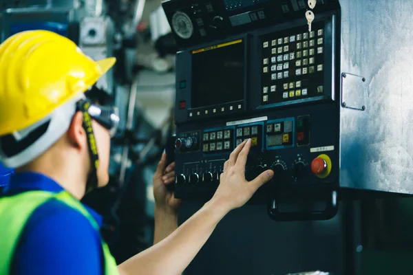 男子工业工程师头戴黄色头盔 站在一家重工业厂房后面 与工人们手握控制权 是该项目的各种金属部件 — 图库照片