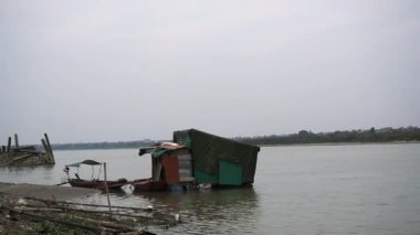 Kirli sahil kenarındaki kulübeler, bir sürü çöp, kum torbaları, ölü hayvanlar, korkunç manzara, Hanoi. Orta boy.