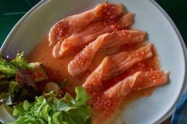 Beyaz tabakta salata ile Tay baharatlı sos Çiğ somon şerit.