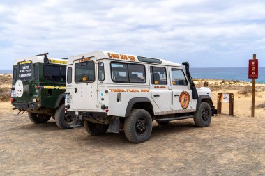 La Graciosa sahiline iki tur aracı park edilmiş, arkada okyanus görünüyor. Bulutlu gökyüzü güzel bir sahne yaratır. Lanzarote, İspanya, 2025-07-20
