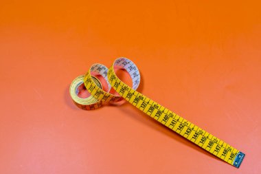 Turuncu zemin üzerinde parlak ışık altında dikiş bandı terziliğinin üzerinden