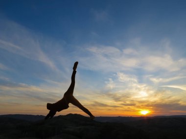 Kızı pratik yoga bir arka planda dağlar ve günbatımı