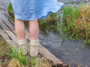 Soğuk yaz. Kadın ayaklarda bot arka planda yeşil çim ve su Gölü hissettim