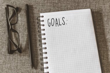 Üstten görünüm defter, kalem, gri kumaş üzerine gözlük ile listesi gol. Yat, alanı Kopyala