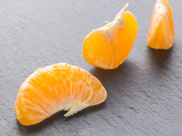 Tangerines slices on black background. Orange mandarin