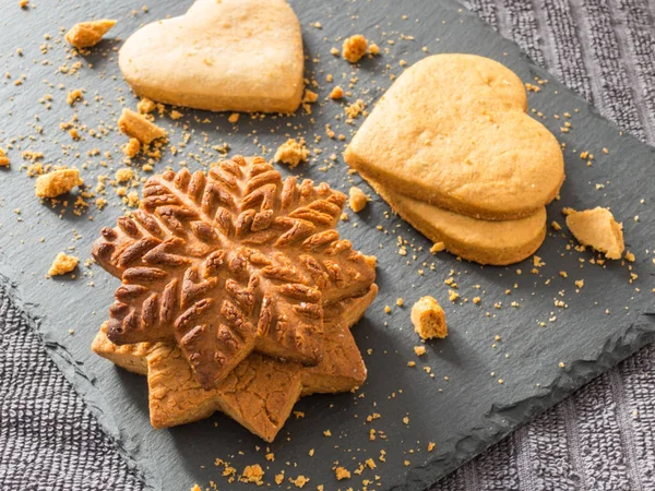 Kar taneleri ve kalpleri bir siyah arka plan üzerine şeklinde sarı zencefilli bisküvi