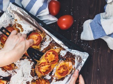 Domates ve peynirle bir fırın tepsisine folyo ile tavuk fileto pişmiş. Lezzetli sağlıklı gıda. Bir yaşam tarzı. Düz yatıyordu. Üstten görünüm. Ahşap arka plan. El