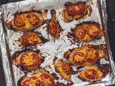 Domates ve peynirle bir fırın tepsisine folyo ile tavuk fileto pişmiş. Lezzetli sağlıklı gıda. Bir yaşam tarzı. Düz yatıyordu. Üstten görünüm. Ahşap arka plan