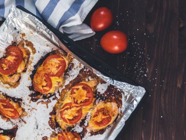Domates ve peynirle bir fırın tepsisine folyo ile tavuk fileto pişmiş. Lezzetli sağlıklı gıda. Bir yaşam tarzı. Düz yatıyordu. Üstten görünüm. Ahşap arka plan