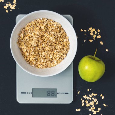 Diyet kavramı, doğru beslenme, sağlıklı yemek. Yulaf ezmesi mutfak terazisi üzerinde beyaz bir tabak içinde. Ürünler ağırlığında. Kahvaltı, üstten görünüm