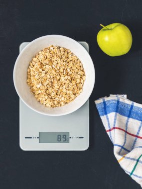 Diyet kavramı, doğru beslenme, sağlıklı yemek. Yulaf ezmesi mutfak terazisi üzerinde beyaz bir tabak içinde. Ürünler ağırlığında. Kahvaltı, üstten görünüm