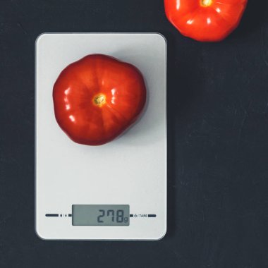 Diyet kavramı, doğru beslenme, sağlıklı yemek. Mutfak terazisi domatese. Ürünler ağırlığında. Üstten görünüm