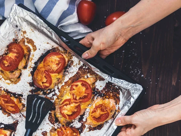 Domates ve peynirle bir fırın tepsisine folyo ile tavuk fileto pişmiş. Lezzetli sağlıklı gıda. Bir yaşam tarzı. Düz yatıyordu. Üstten görünüm. Ahşap arka plan. El