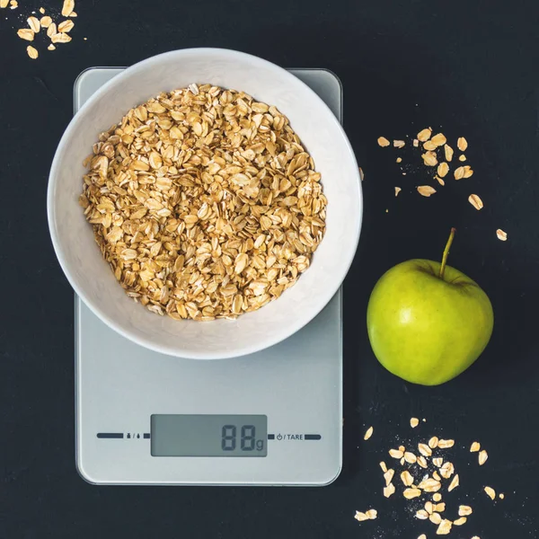 Diyet kavramı, doğru beslenme, sağlıklı yemek. Yulaf ezmesi mutfak terazisi üzerinde beyaz bir tabak içinde. Ürünler ağırlığında. Kahvaltı, üstten görünüm