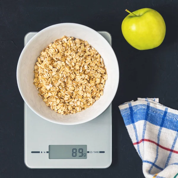 Diyet kavramı, doğru beslenme, sağlıklı yemek. Yulaf ezmesi mutfak terazisi üzerinde beyaz bir tabak içinde. Ürünler ağırlığında. Kahvaltı, üstten görünüm