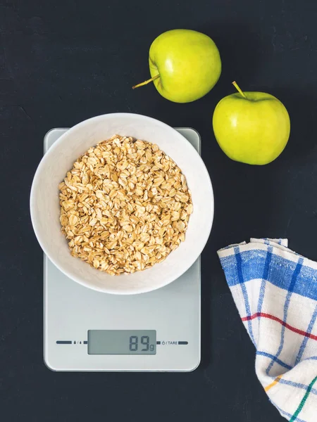 Diyet kavramı, doğru beslenme, sağlıklı yemek. Yulaf ezmesi mutfak terazisi üzerinde beyaz bir tabak içinde. Ürünler ağırlığında. Kahvaltı, üstten görünüm