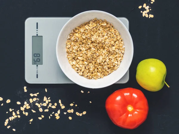 Diyet kavramı, doğru beslenme, sağlıklı yemek. Yulaf ezmesi mutfak terazisi üzerinde beyaz bir tabak içinde. Ürünler ağırlığında. Kahvaltı, üstten görünüm