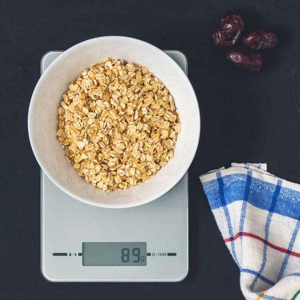 Diyet kavramı, doğru beslenme, sağlıklı yemek. Yulaf ezmesi mutfak terazisi üzerinde beyaz bir tabak içinde. Ürünler ağırlığında. Kahvaltı, üstten görünüm