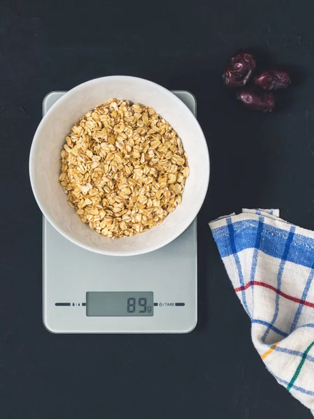 Diyet kavramı, doğru beslenme, sağlıklı yemek. Yulaf ezmesi mutfak terazisi üzerinde beyaz bir tabak içinde. Ürünler ağırlığında. Kahvaltı, üstten görünüm