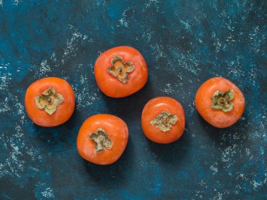 Olgun turuncu incir Trabzon hurması meyve mavi grunge arka plan üzerinde. Düz yatıyordu. Üstten görünüm. Kopya alanı