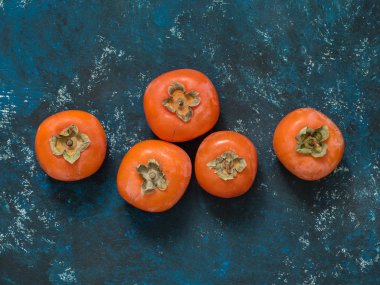 Olgun turuncu incir Trabzon hurması meyve mavi grunge arka plan üzerinde. Düz yatıyordu. Üstten görünüm. Kopya alanı