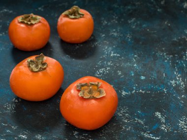 Olgun turuncu incir Trabzon hurması meyve mavi grunge arka plan üzerinde. Düz yatıyordu. Üstten görünüm. Kopya alanı