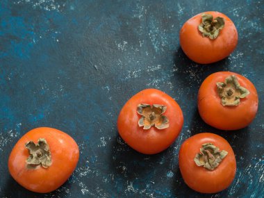 Olgun turuncu incir Trabzon hurması meyve mavi grunge arka plan üzerinde. Düz yatıyordu. Üstten görünüm. Kopya alanı