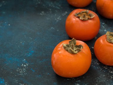 Olgun turuncu incir Trabzon hurması meyve mavi grunge arka plan üzerinde. Düz yatıyordu. Üstten görünüm. Kopya alanı