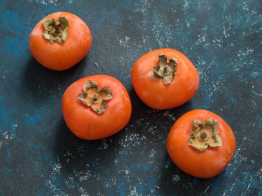 Olgun turuncu incir Trabzon hurması meyve mavi grunge arka plan üzerinde. Düz yatıyordu. Üstten görünüm. Kopya alanı