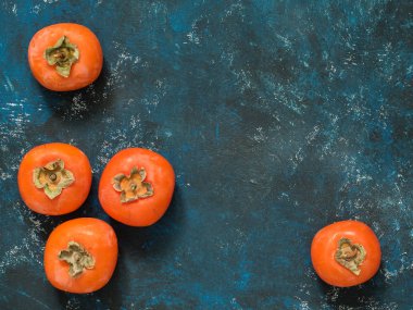 Olgun turuncu incir Trabzon hurması meyve mavi grunge arka plan üzerinde. Düz yatıyordu. Üstten görünüm. Kopya alanı
