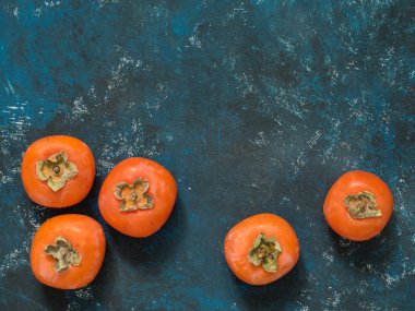 Olgun turuncu incir Trabzon hurması meyve mavi grunge arka plan üzerinde. Düz yatıyordu. Üstten görünüm. Kopya alanı