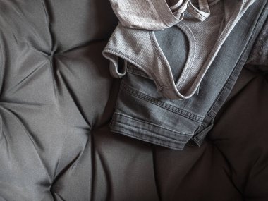 Gri Bayan giyim gri bir sandalyeye. Gömlek, kot pantolon. Nötr arka plan