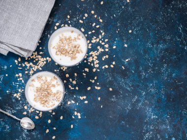 Sağlıklı kahvaltı. Yoğurtlu yulaf gevreği mavi bir arka plan üzerinde beyaz gözlük. Düz yatıyordu, en iyi görünüm, kopya alanı