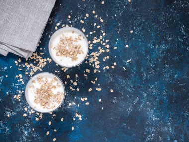 Sağlıklı kahvaltı. Yoğurtlu yulaf gevreği mavi bir arka plan üzerinde beyaz gözlük. Düz yatıyordu, en iyi görünüm, kopya alanı