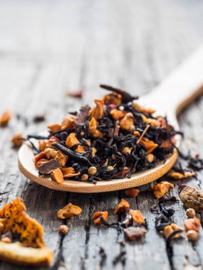 Ahşap arka plan üzerinde siyah meyve çay tarçın, elma, portakal, kişniş, kakule, karanfil ve tahta kaşık kırmızı biber ile kuru yapraklar