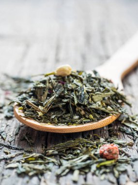 Kuru Sencha yeşil çiçek çay yaprakları ile Fuska yaprak, frenk üzümü, Yasemin, gül yaprakları, tatlım granülleri, Orman berry aroma ahşap arka plan ağaç kaşık içinde